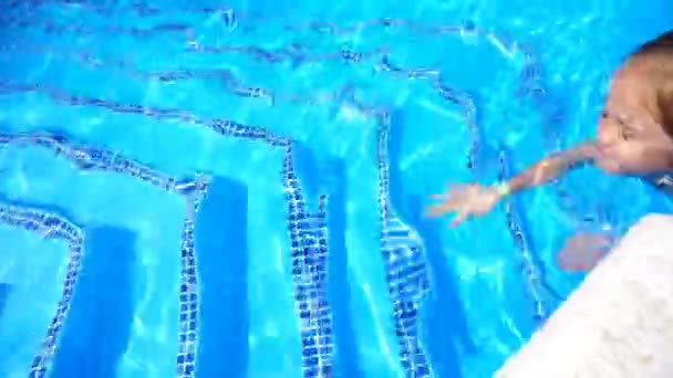 Красавица маленькая девочка плавает в открытом бассейне и веселится — стоковое видео