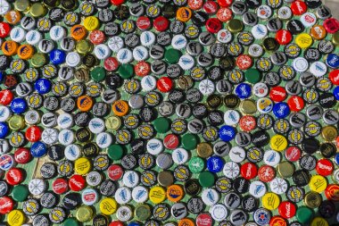 Krasnodar, Russia - April 29, 2018: Beer bottle caps, a mix of global brands: Chesters , Gletcher, Coca-Cola etc. clipart