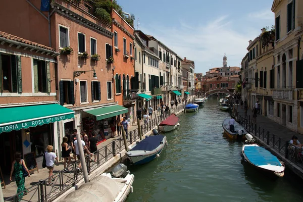 VENICE, ITÁLIA - 02 de agosto de 2019: Um dos milhares de belos cantos aconchegantes em Veneza em um dia ensolarado claro. Locais e turistas passeando pelos edifícios históricos e canais com barcos ancorados — Fotografia de Stock