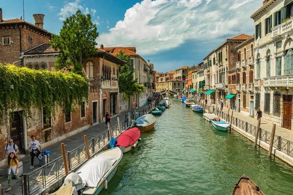 VENICE, ITALY - August 02, 2019: One of the thousands of lovely cozy corners in Venice on a clear sunny day. Locals and tourists strolling along the historical buildings and canals with moored boats — Stock Photo, Image