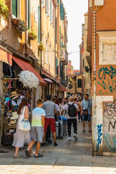 VENECIA, ITALIA - 02 de agosto de 2019: Calles peatonales estrechas de Venecia. Locales y turistas paseando por los edificios históricos, escaparates, souvenirs, cafés y restaurantes — Foto de Stock
