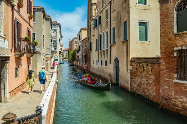 VENECIA, ITALIA - 02 de agosto de 2019: Uno de los miles de rincones acogedores de Venecia en un día claro y soleado. Locales y turistas paseando por los edificios históricos y canales con embarcaciones amarradas — Foto de Stock