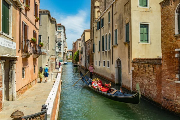 VENECIA, ITALIA - 02 de agosto de 2019: Uno de los miles de rincones acogedores de Venecia en un día claro y soleado. Locales y turistas paseando por los edificios históricos y canales con embarcaciones amarradas — Foto de Stock