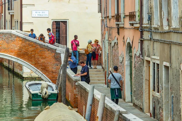 Venedig, Italien - 02. August 2019: enge Fußgängergassen in Venedig. Einheimische und Touristen flanieren entlang der historischen Gebäude, Schaufenster, Souvenirs, Cafés und Restaurants — Stockfoto