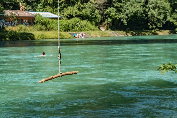 Bern, Svájc - 2019. július 30.: Kilátás az Aare folyóra a napos nyári napon. A helyi lakosok pihenhetnek, napozhatnak és raftingolhatnak felfújható csónakokban a folyó gyors folyása mentén. — Stock Fotó