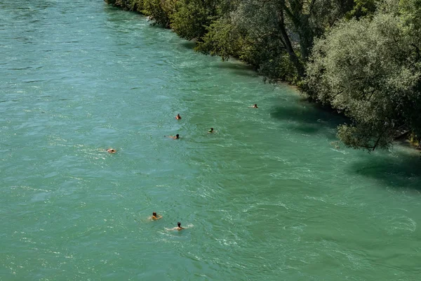 Bern, Zwitserland - 30 juli 2019: Zicht op de rivier de Aare op zonnige zomerdag. Lokale bewoners ontspannen, zonnebaden en raften in opblaasbare boten langs de snelle stroming van de rivier — Stockfoto