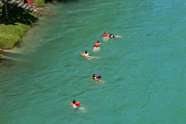 Bern, Switzerland - July 30, 2019: View of Aare river at sunny summer day. Local residents relax, sunbathe and rafting in inflatable boats along the fast flow of the river — Stock Photo, Image