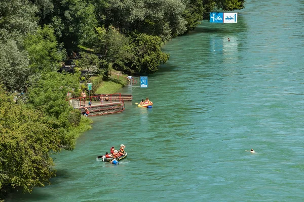 Bern, Svájc - 2019. július 30.: Kilátás az Aare folyóra a napos nyári napon. A helyi lakosok pihenhetnek, napozhatnak és raftingolhatnak felfújható csónakokban a folyó gyors folyása mentén. — Stock Fotó