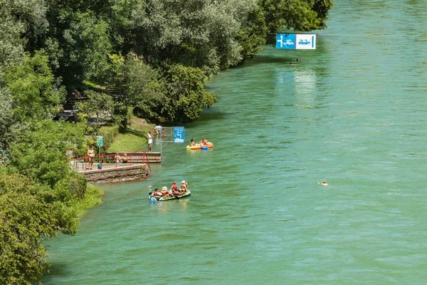 Bern, Svájc - 2019. július 30.: Kilátás az Aare folyóra a napos nyári napon. A helyi lakosok pihenhetnek, napozhatnak és raftingolhatnak felfújható csónakokban a folyó gyors folyása mentén. — Stock Fotó