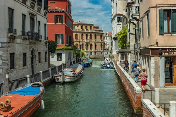 VENECIA, ITALIA - 02 de agosto de 2019: Uno de los miles de rincones acogedores de Venecia en un día claro y soleado. Locales y turistas paseando por los edificios históricos y canales con embarcaciones amarradas — Foto de Stock