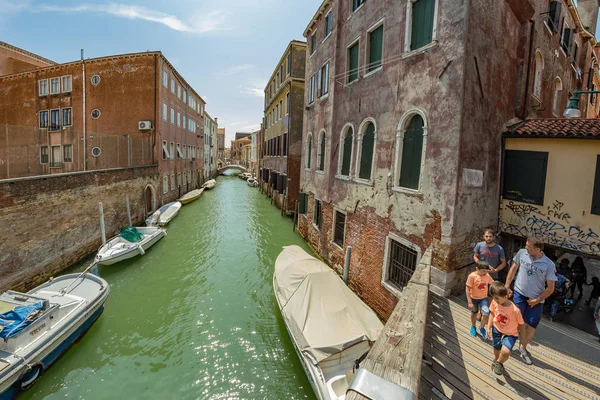 Venedig, Italien - 02. August 2019: eine der tausenden schönen gemütlichen Ecken Venedigs an einem klaren, sonnigen Tag. Einheimische und Touristen flanieren mit festgemachten Booten entlang der historischen Gebäude und Kanäle — Stockfoto