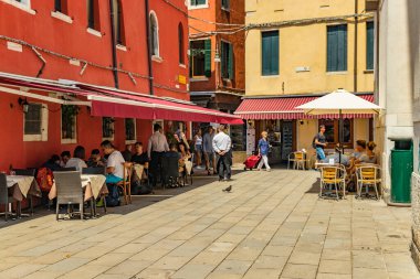 VENICE, ITALY - August 02, 2019: One of the thousands of lovely cozy corners in Venice on a clear sunny day. Locals and tourists strolling along the streets and historical buildings.