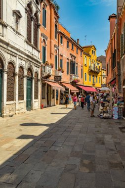 VENICE, ITALY - August 02, 2019: One of the thousands of lovely cozy corners in Venice on a clear sunny day. Locals and tourists strolling along the streets and historical buildings.