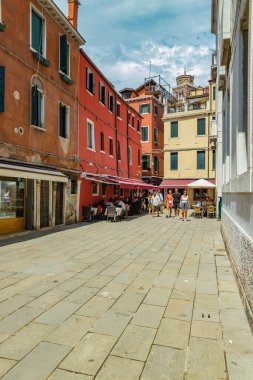 VENICE, ITALY - August 02, 2019: One of the thousands of lovely cozy corners in Venice on a clear sunny day. Locals and tourists strolling along the streets and historical buildings.