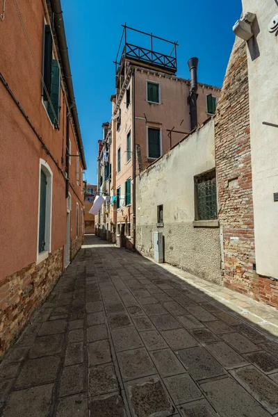 VENICE, ITALY - August 03, 2019: One of the thousands of lovely cozy corners in Venice on a clear sunny day. Locals and tourists strolling along the streets and historical buildings.