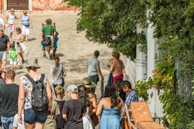 VENICE, ITALY - August 02, 2019: One of the thousands of lovely cozy corners in Venice on a clear sunny day. Locals and tourists strolling along the streets and historical buildings.