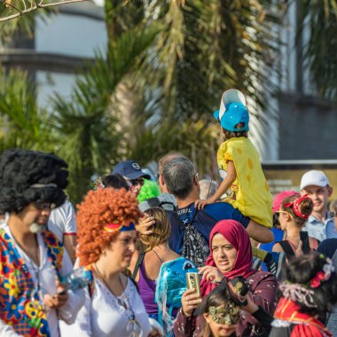 SANTA CRUZ DE TENERIFE, SPAIN - FEBRUARY 25, 2020: Around the Coso parade - along the Avenida de Anaga, official end of Carnival. Amazing warm evening, joyful people in carnival costumes have fun.