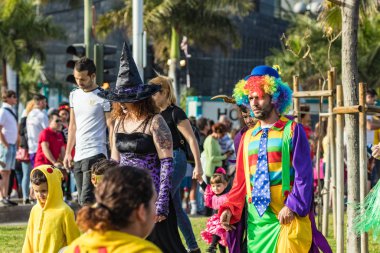SANTA CRUZ DE TENERIFE, SPAIN - FEBRUARY 25, 2020: Around the Coso parade - along the Avenida de Anaga, official end of Carnival. Amazing warm evening, joyful people in carnival costumes have fun.