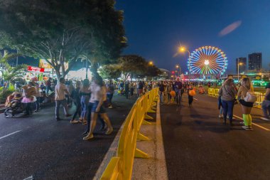 SANTA CRUZ DE TENERIFE, SPAIN - FEBRUARY 25, 2020: Around the Coso parade - along the Avenida de Anaga, official end of Carnival. Amazing warm evening, joyful people in carnival costumes have fun.