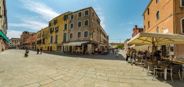 VENICE, ITALY - August 02, 2019: One of the thousands of lovely cozy corners in Venice on a clear sunny day. Locals and tourists strolling along the streets and historical buildings.