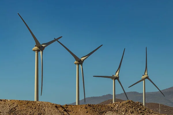 Wind power stations. A row of turbines near the seashore. Wind farm eco field. Eolic park with blue sky in background. Green, ecological and power energy generation concept.