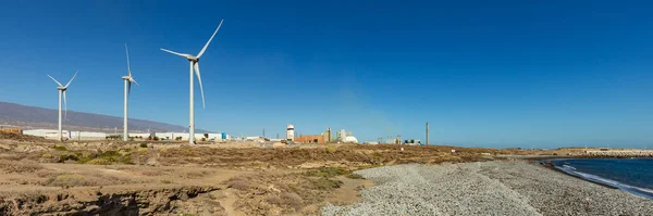 Super wide panorama of Wind power station. A row of turbines near the seashore. Wind farm eco field. Eolic park with blue sky in background. Green, ecological and power energy generation concept.