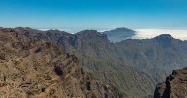 Ulusal Park Caldera de Taburiente 'nin hava manzarası, Roque de los Muchachos' un dağ zirvesinden görülen volkanik krater. El Hierro bulutların üzerinde ufukta. La Palma, İspanya