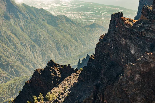 Telephoto lens shot. Aerial view of the National Park Caldera de Taburiente, volcanic crater seen from Roque de los Muchachos Viewpoint. Tenerife in the background above the clouds. La Palma, Spain