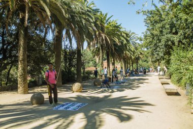 BARCELONA, İspanya - 22 Haziran 2016: İnsanlar Park Guell 'de yürüyüş yapıyor ve eğleniyor. Gaudi müzesi ve panoramik manzaralı yeşil bir park. Mimar Gaudi. Açık mavi gökyüzü ile güzel bir yaz günü.