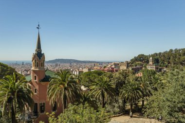 BARCELONA, İspanya - 22 Haziran 2016: İnsanlar Park Guell 'de yürüyüş yapıyor ve eğleniyor. Gaudi müzesi ve panoramik manzaralı yeşil bir park. Mimar Gaudi. Açık mavi gökyüzü ile güzel bir yaz günü.