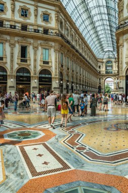 MİLAN, İtalya - 1 AĞUSTOS 2019: Milano 'da güzel bir yaz gününde ünlü Galleria Vittorio Emanuele II. Dükkanlar, butikler, kafeler arasında turistler ve yerliler yürüyor.
