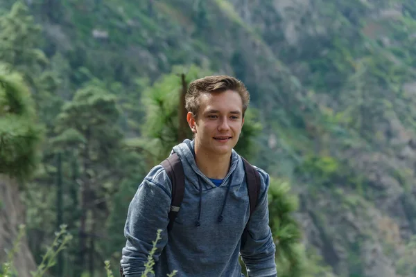 A young man with a backpack travels along a route in the west side of Tenerife. Hiking by the mountain trail surrounded by endemic vegetation pine tree forest and fields of lava rocks. Canary Islands.