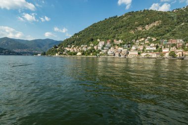 Como, ITALY - 4 Ağustos 2019: Como Gölü yakınlarındaki yeşil ormanlık dağlarda daireler, villalar, oteller. Güzel İtalyan Como şehri. Çok popüler bir tatil merkezinde, güneşli bir yaz günü..