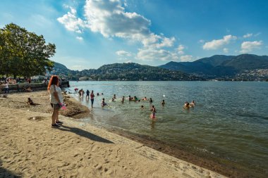 Como, ITALY - 4 Ağustos 2019: Güzel İtalyan Como şehrinin göl kenarındaki gezinti alanında yerel halk ve turistler. Çok popüler bir tatil merkezinde, güneşli bir yaz günü.