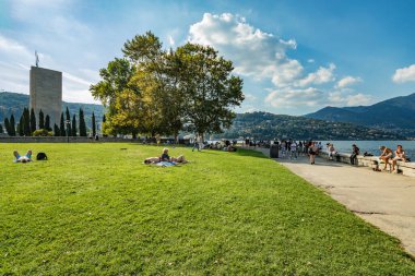 Como, ITALY - 4 Ağustos 2019: Güzel İtalyan Como şehrinin göl kenarındaki gezinti alanında yerel halk ve turistler. Çok popüler bir tatil merkezinde, güneşli bir yaz günü.