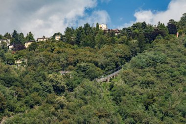 Como, ITALY - 4 Ağustos 2019: Como Gölü yakınlarındaki yeşil ormanlık dağlarda daireler, villalar, oteller. Güzel İtalyan Como şehri. Çok popüler bir tatil merkezinde, güneşli bir yaz günü..