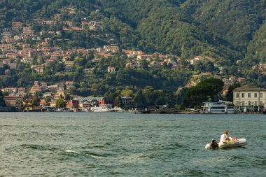 Como, ITALY - 4 Ağustos 2019: Como Gölü yakınlarındaki yeşil ormanlık dağlarda daireler, villalar, oteller. Güzel İtalyan Como şehri. Çok popüler bir tatil merkezinde, güneşli bir yaz günü..