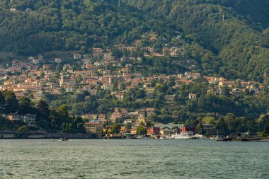 Como, ITALY - 4 Ağustos 2019: Como Gölü yakınlarındaki yeşil ormanlık dağlarda daireler, villalar, oteller. Güzel İtalyan Como şehri. Çok popüler bir tatil merkezinde, güneşli bir yaz günü..