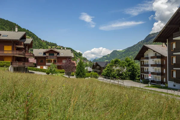 İsviçre 'nin küçük Champery tatil köyünden İsviçre Alpleri' nin karlı dağ zirvelerinin muhteşem manzarası. Parlak mavi gökyüzü ve kayalık tepelerin üzerinde beyaz kabarık bulutlar. Yol boyunca kadehler.