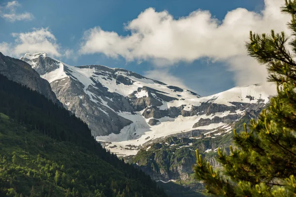 İsviçre 'nin küçük Champery tatil köyünden İsviçre Alpleri' nin karlı dağ zirvelerinin muhteşem manzarası. Parlak mavi gökyüzü ve kayalık tepelerin üzerinde beyaz kabarık bulutlar.