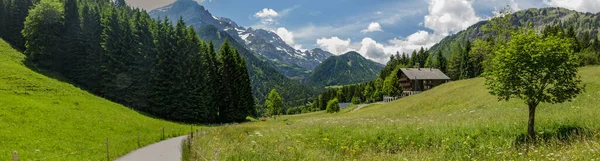 İsviçre 'nin küçük Champery tatil köyünden İsviçre Alpleri' nin karlı dağ zirvelerinin muhteşem manzarası. Parlak mavi gökyüzü ve kayalık tepelerin üzerinde beyaz kabarık bulutlar.