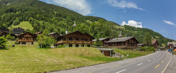 Klasik İsviçre dağ evi, yeşil alp çayırlarının ortasında. İsviçre 'nin kırsal kesimindeki Champery kasabasında. Parlak mavi gökyüzü ve kayalık tepelerin üzerinde beyaz kabarık bulutlar.