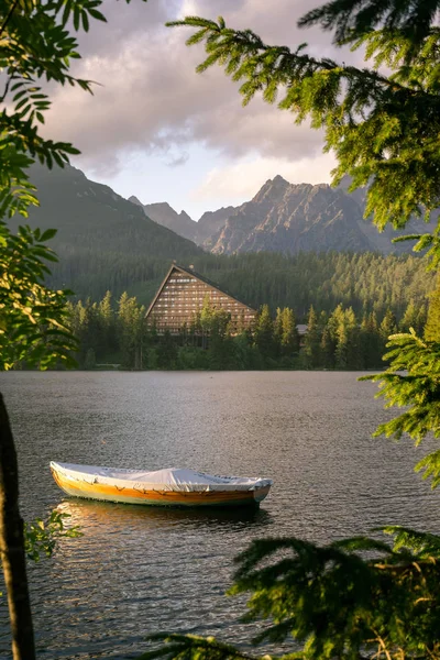 Peaceful mountain scene with hotel next to a lake with boat.