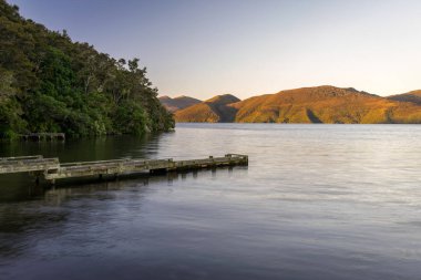 Gün batımı göl ile ahşap iskele üzerinde.