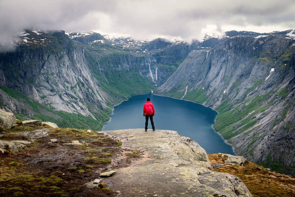 Young female hiker enjoying beautiful view of dramatic landscape in a Norway.