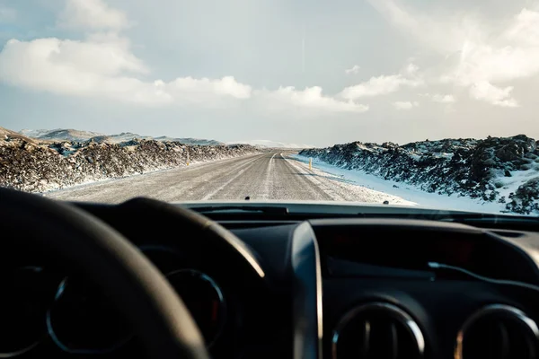 Driving in icelandic winter. Blowing snow across the road. Difficult driving conditions in winter season in Iceland. Sunny but windy day, typical Icelandic route troubles. Icelandic safety driving.