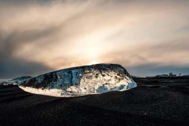 Jokulsarlon buzul lagoon yakınındaki siyah volkanik sahilde buz, İzlanda kış. Güzel bir akşam ışık siyah kum Plajı'nda buz buzul parçası detay.