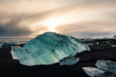 Jokulsarlon buzul lagoon yakınındaki siyah volkanik sahilde buz, İzlanda kış. Güzel bir akşam ışık siyah kum Plajı'nda buz buzul parçası detay.