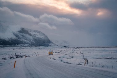 Güzel görünüm ve kış İzlanda'nın altın daire yol inşaatı sırasında arka plan olarak karla kaplı dağ ve bir ön plan olarak yol asfalt günbatımı manzara.