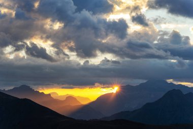Kırmızı günbatımı güneşli kiriş dağlar manzara içinde. Güneş Yüksek dağların arkasında peaking ile İtalyan Dolomites dramatik sahne.